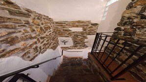 Una estrecha escalera de piedra con barandilla metálica, que desciende a un nivel inferior.