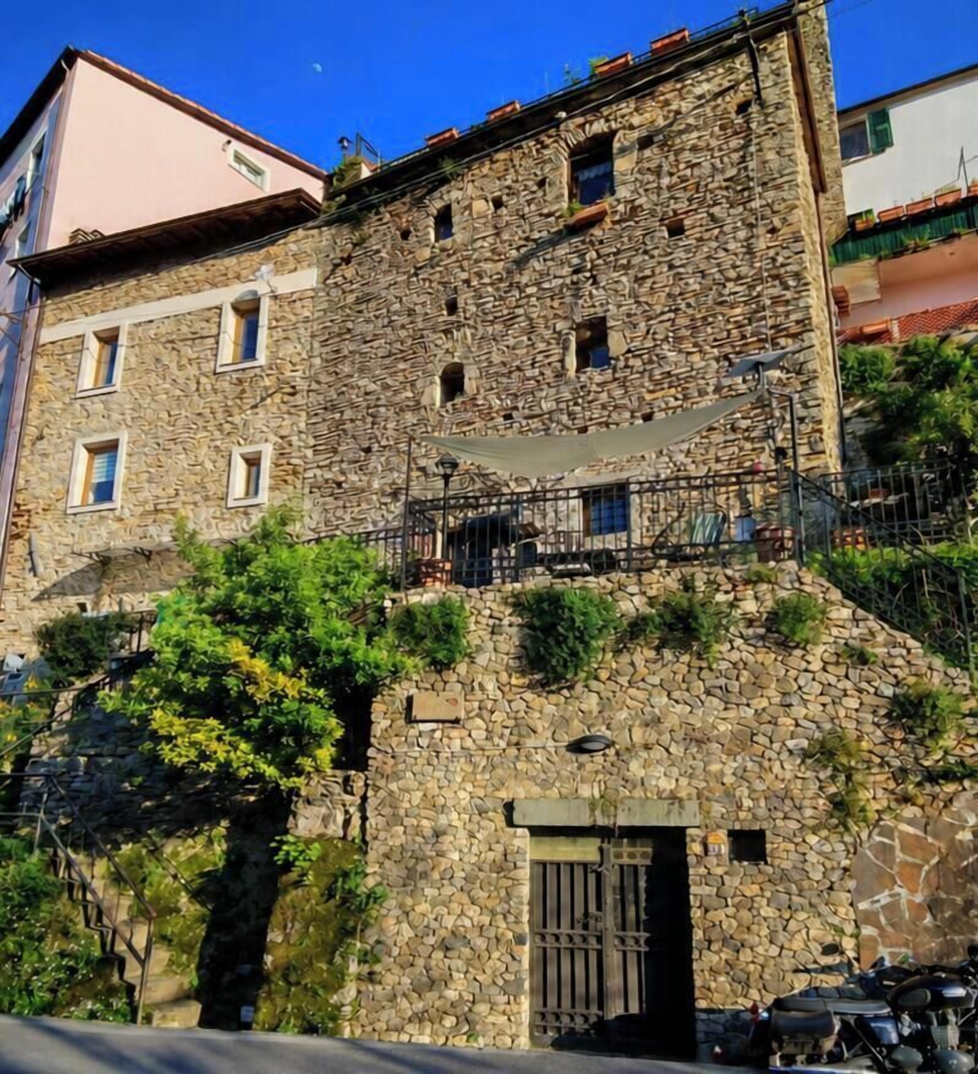 A stone building with a balcony, a door, and a staircase leading to an upper level.