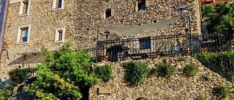 A stone building with a balcony, a door, and a staircase leading to an upper level.