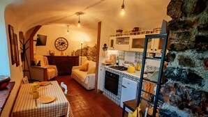 Una cocina acogedora con pared de piedra, una zona de comedor con mantel a cuadros y un rincón de estar con sofá.