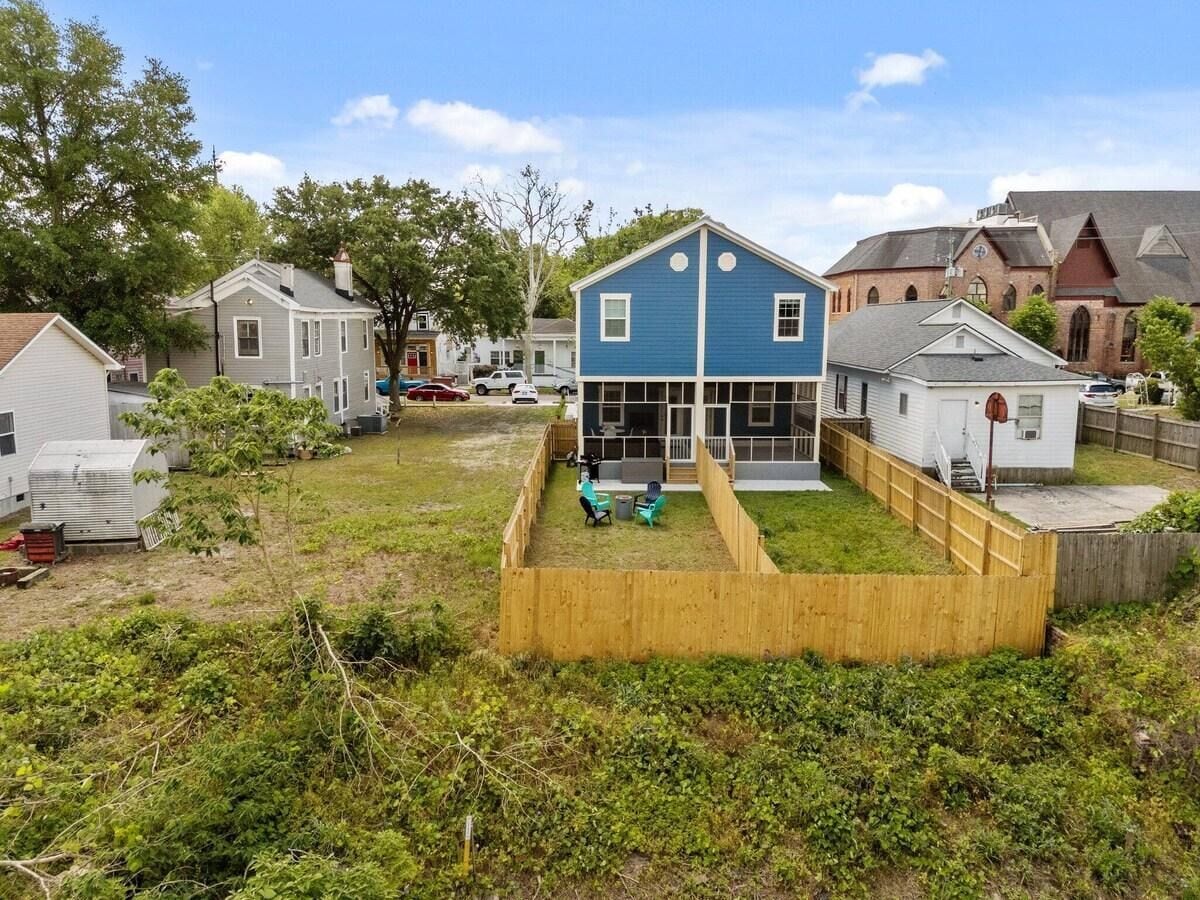 Un barrio residencial con una casa azul, un patio cercado y una iglesia al fondo.
