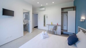 Une chambre d’hôtel moderne équipée d’un lit, d’un bureau, d’une chaise, d’une télévision et d’une salle de bain.