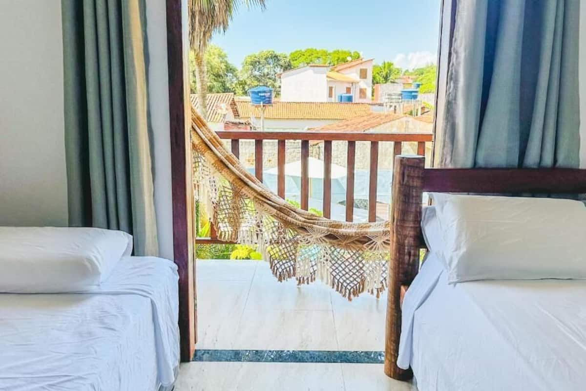 A hotel room with two beds, a wooden headboard, and a view of a balcony with a hammock.
