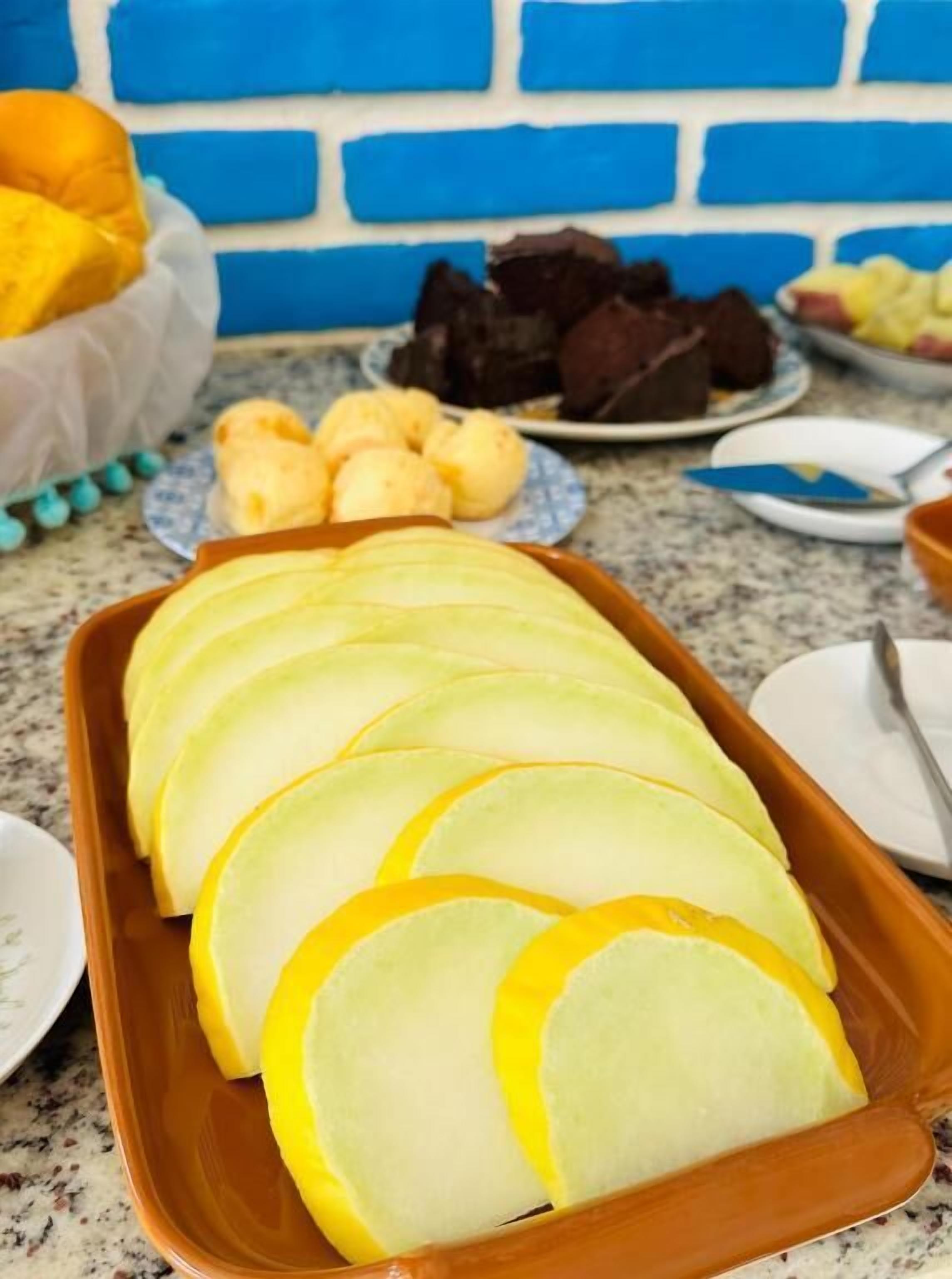 Una encimera de cocina con rebanadas de manzana, un plato de pasteles y un muro de ladrillo azul al fondo.