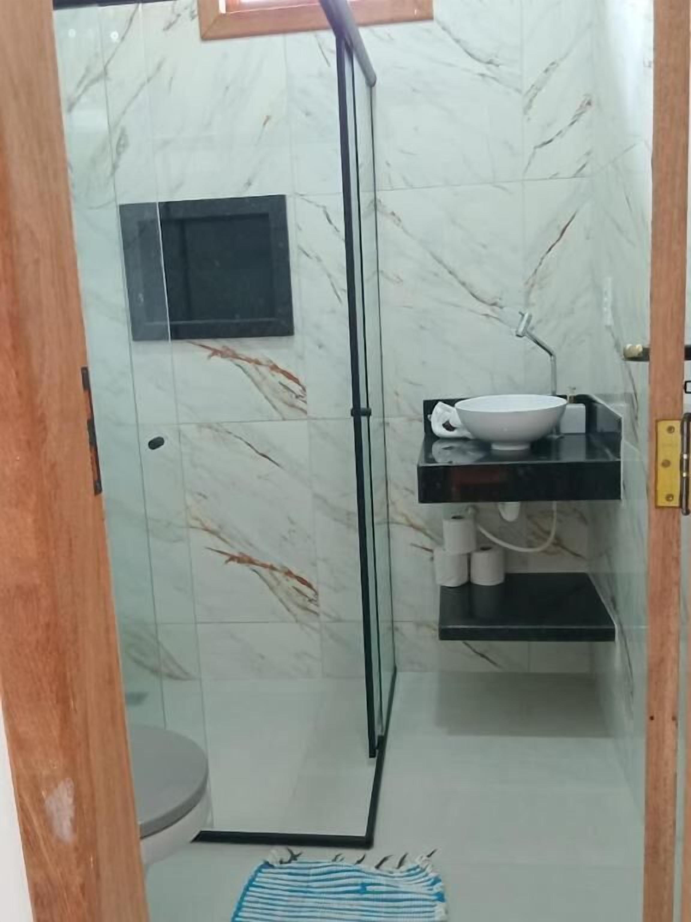 A bathroom with a glass shower enclosure, a white sink with a bowl, and a toilet.