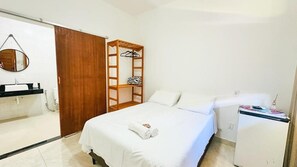 Ein Hotelzimmer mit einem Bett, einem Holzschrank, einem Spiegel, einem kleinen Tisch und einem Kühlschrank.