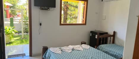 Una habitación con dos camas, televisión, aire acondicionado y ventana con vistas a zonas verdes.