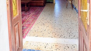 Un salon avec un canapé en cuir marron, un tapis à motifs et un mur vert orné de tableaux encadrés.