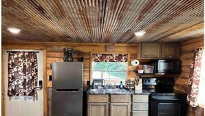 A compact kitchen with wooden cabinets, a stainless steel refrigerator, a microwave, and a stove. - Buffalo River Cowboy Cabin Getaway and HOT TUB! (Compton)