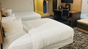 Una camera d'albergo con due letti, una scrivania con una sedia, una televisione e uno specchio.