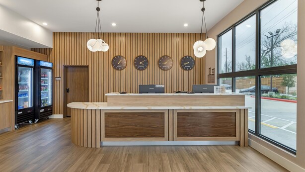 Un'area reception con scrivania in legno, due frigoriferi e orologi che mostrano nomi di diverse città.