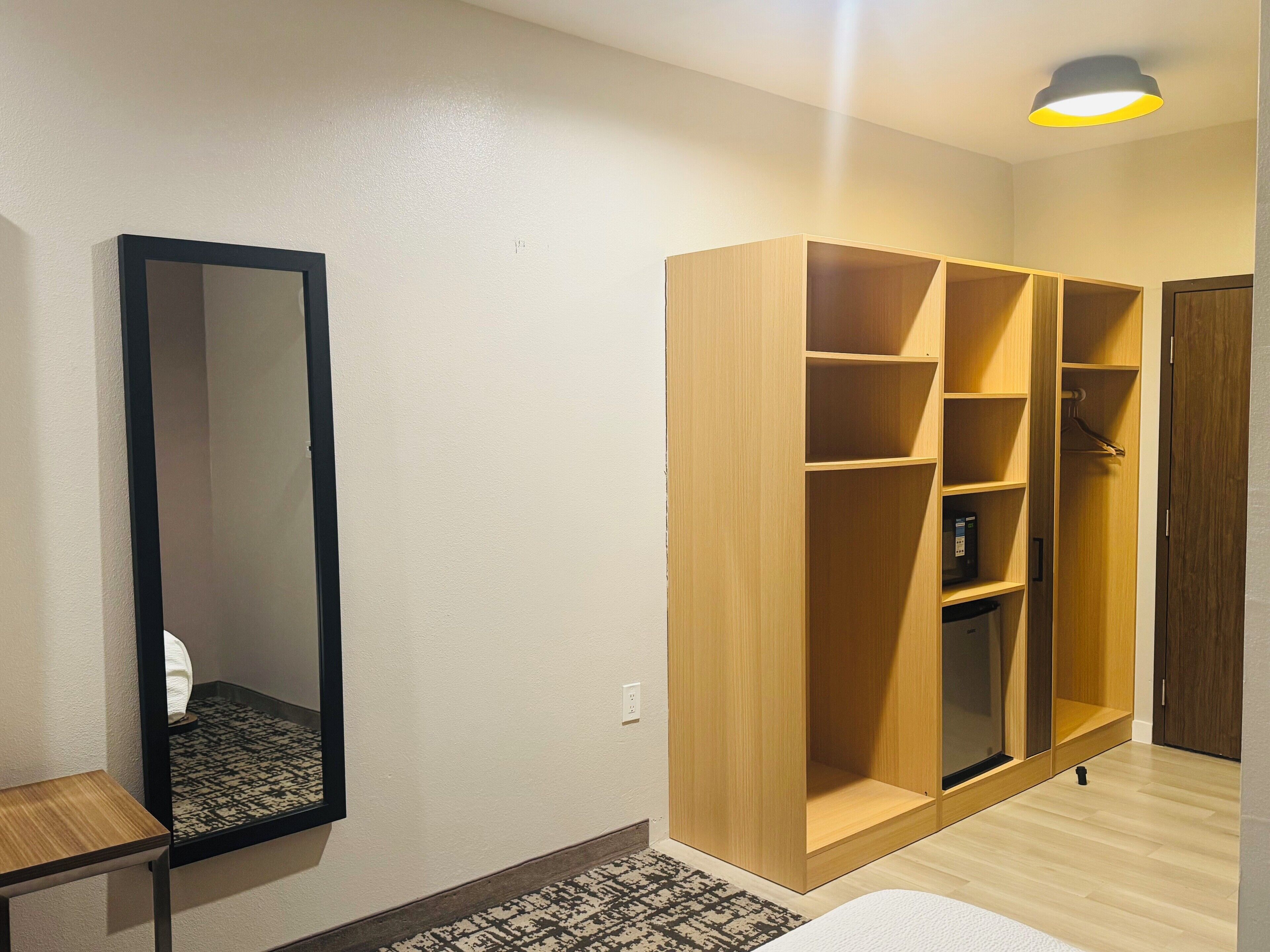 Una habitación con un armario grande, un espejo y una mesita.