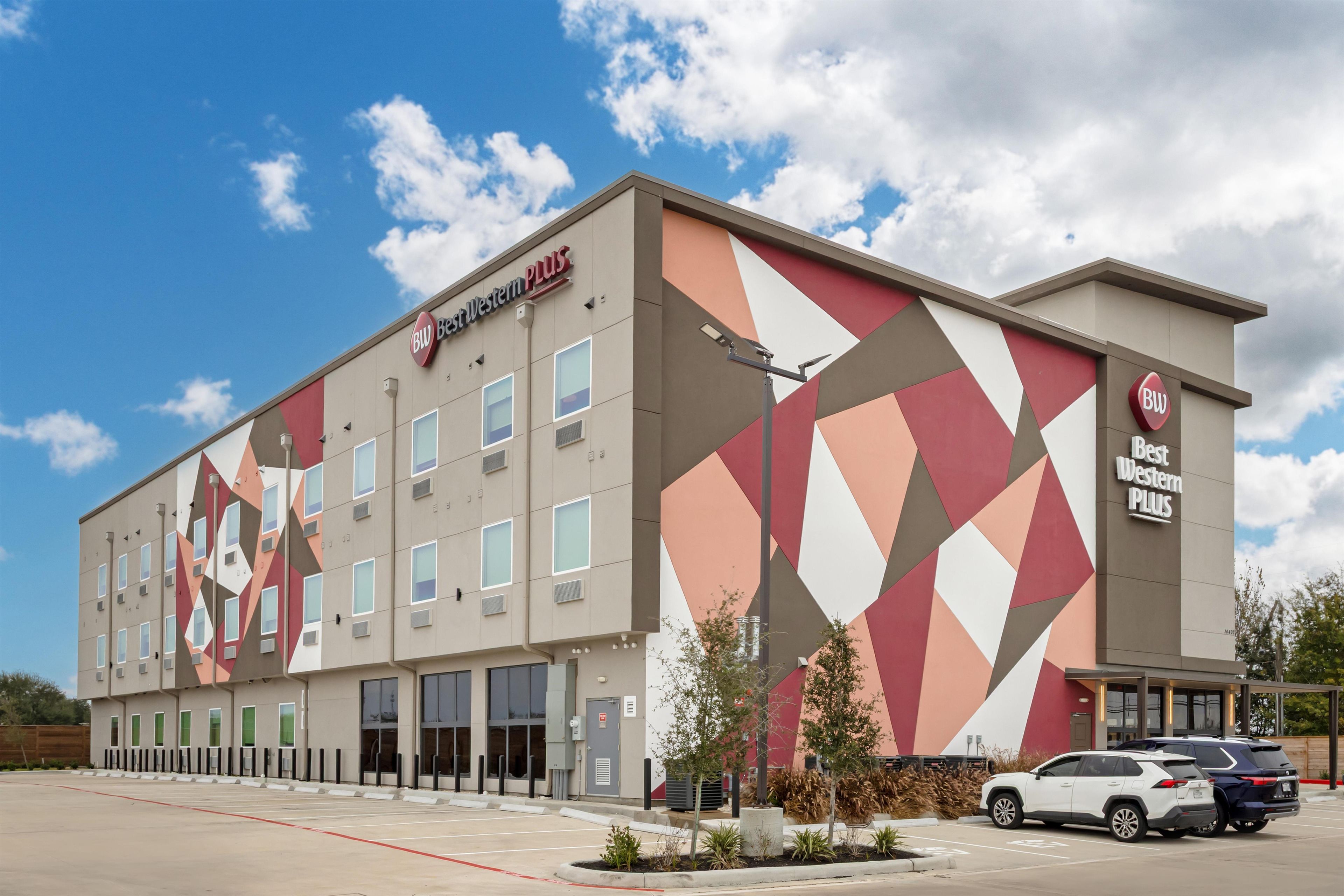 Et Best Western Plus hotel med et geometrisk facade design, mange vinduer og en parkeringsplads med flere biler.