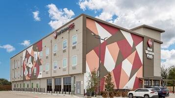 Et Best Western Plus hotel med et geometrisk facade design, mange vinduer og en parkeringsplads med flere biler.