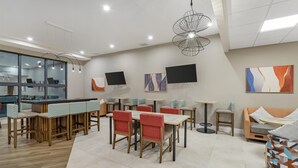 Una moderna hall d'albergo con area bar, posti a sedere e opere d'arte alle pareti.