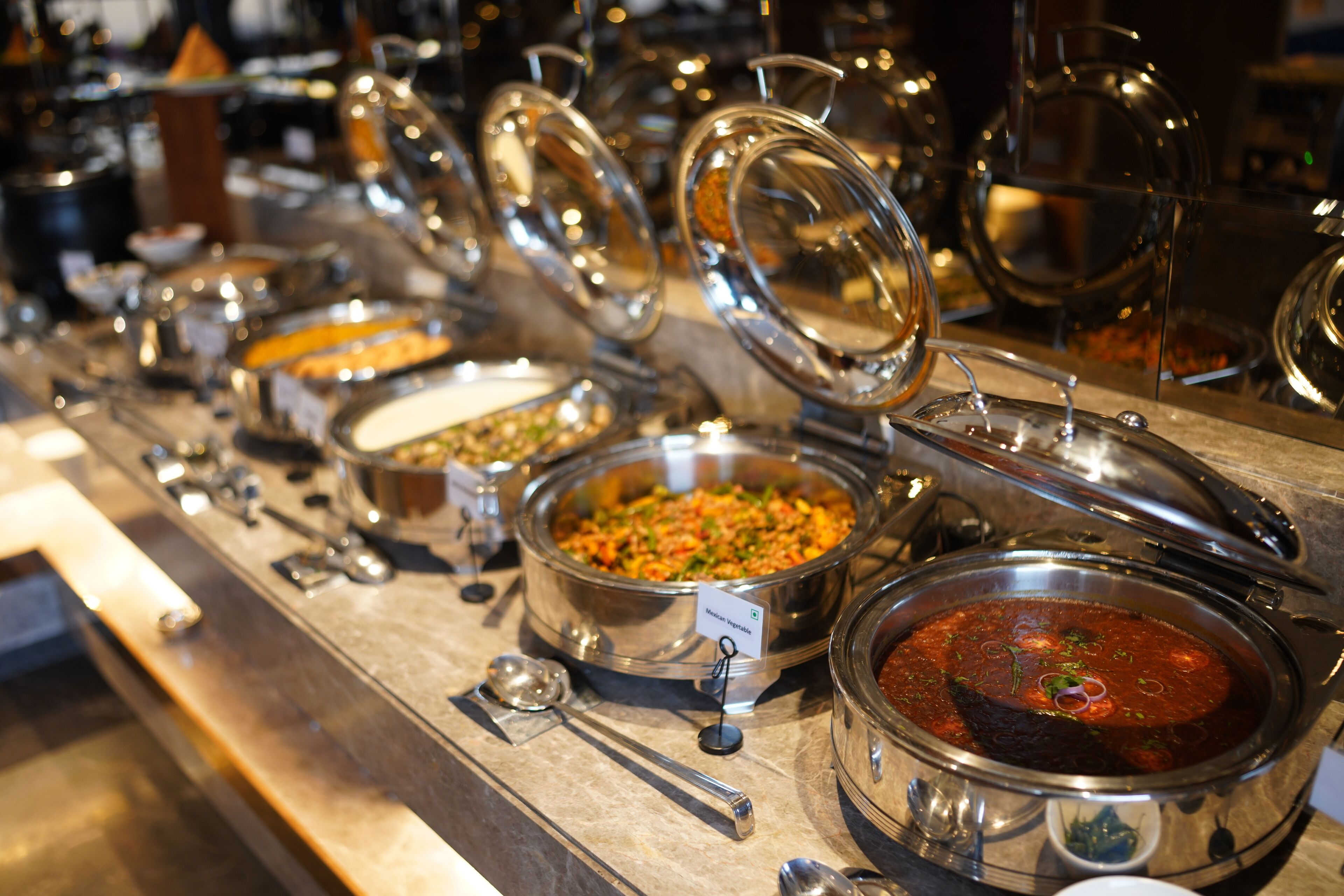 A buffet with various dishes in stainless steel serving containers.