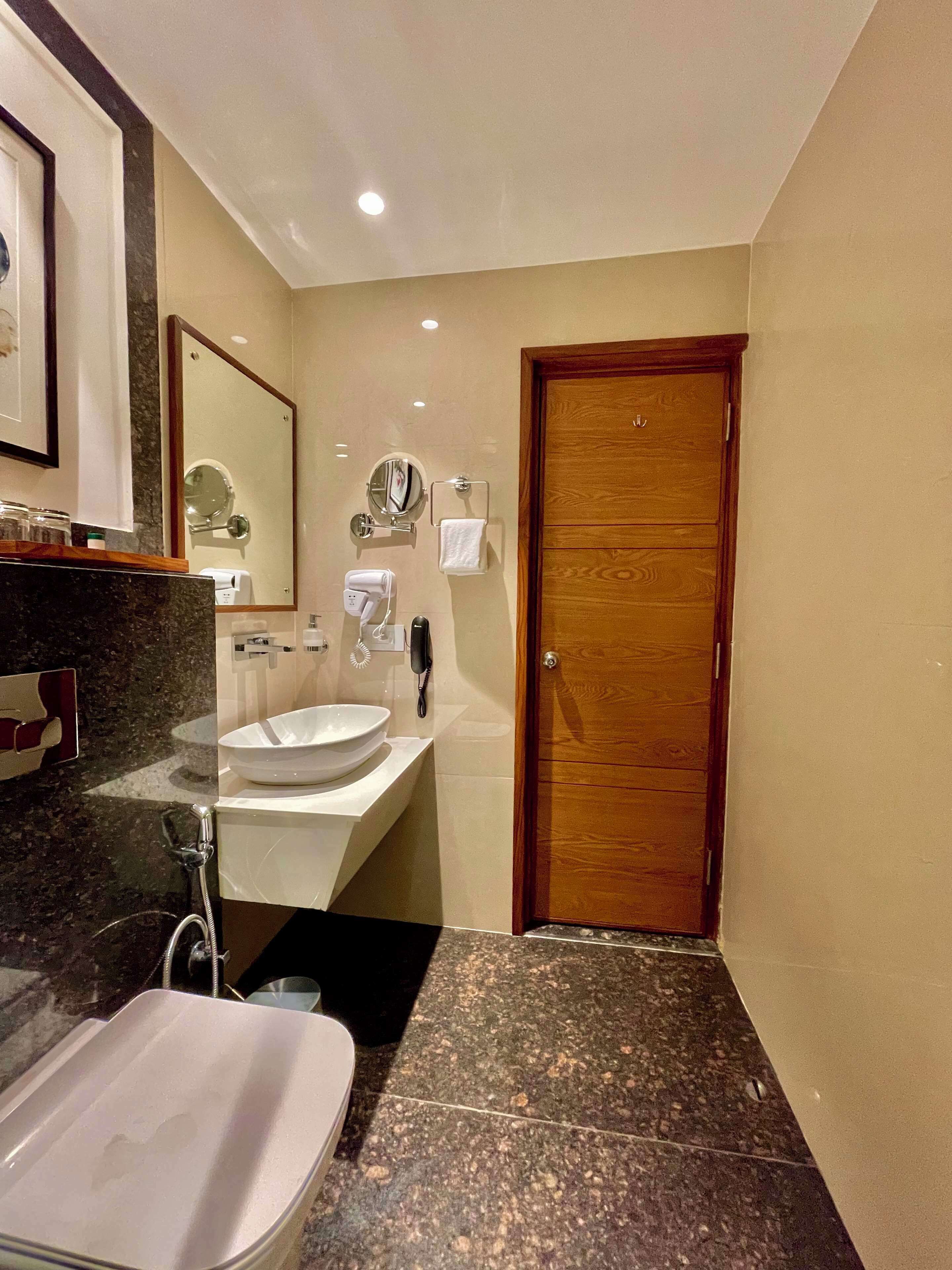 A modern bathroom with a large sink, mirror, and a wooden door.