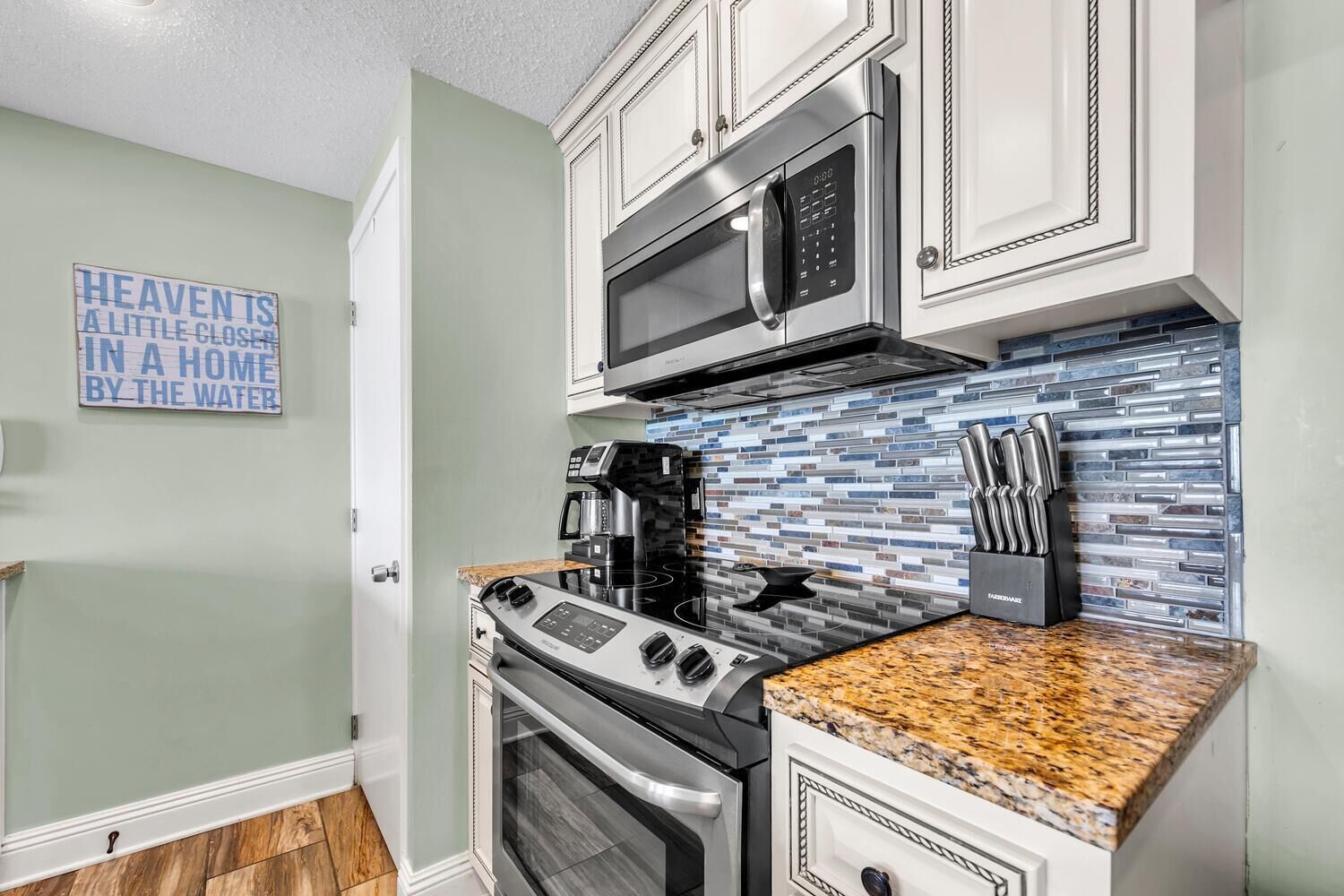 A modern kitchen with a stainless steel stove, microwave, and coffee maker.