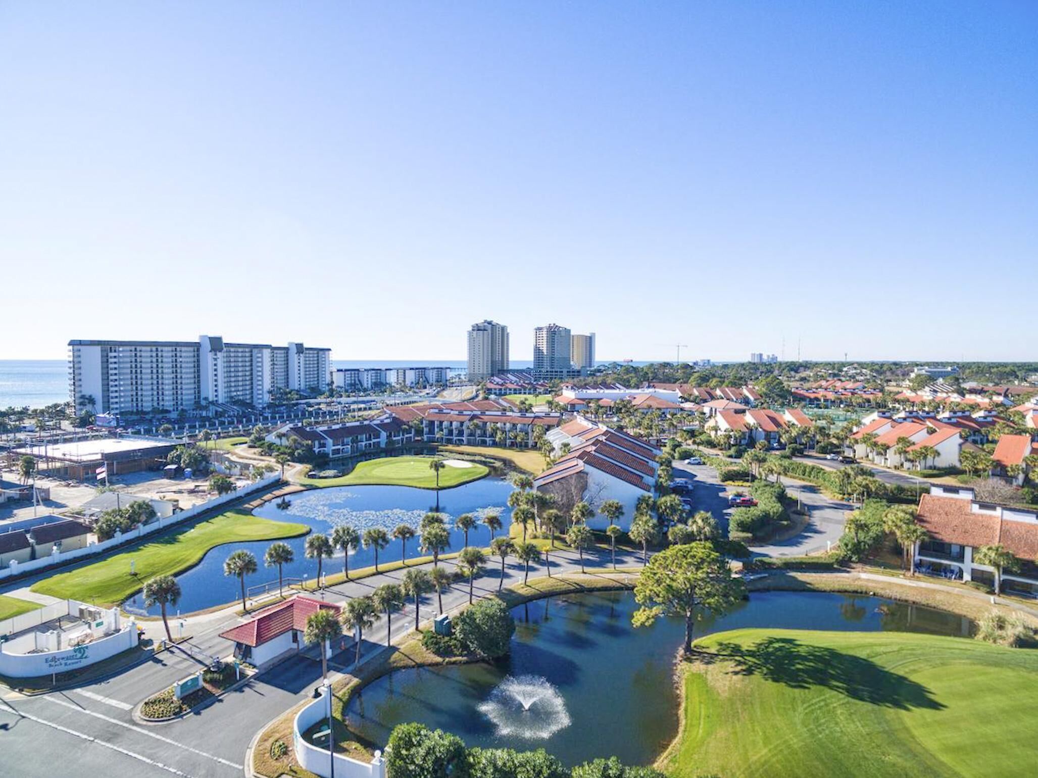 A resort with multiple buildings, a golf course, and a large body of water.