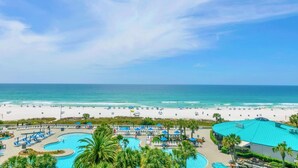 Een resort met een groot zwembad, toegang tot het strand en een helder uitzicht op de oceaan.