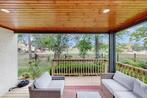 Relax in this serene outdoor space with a view of the fenced yard, featuring two comfortable sofas and a small table.