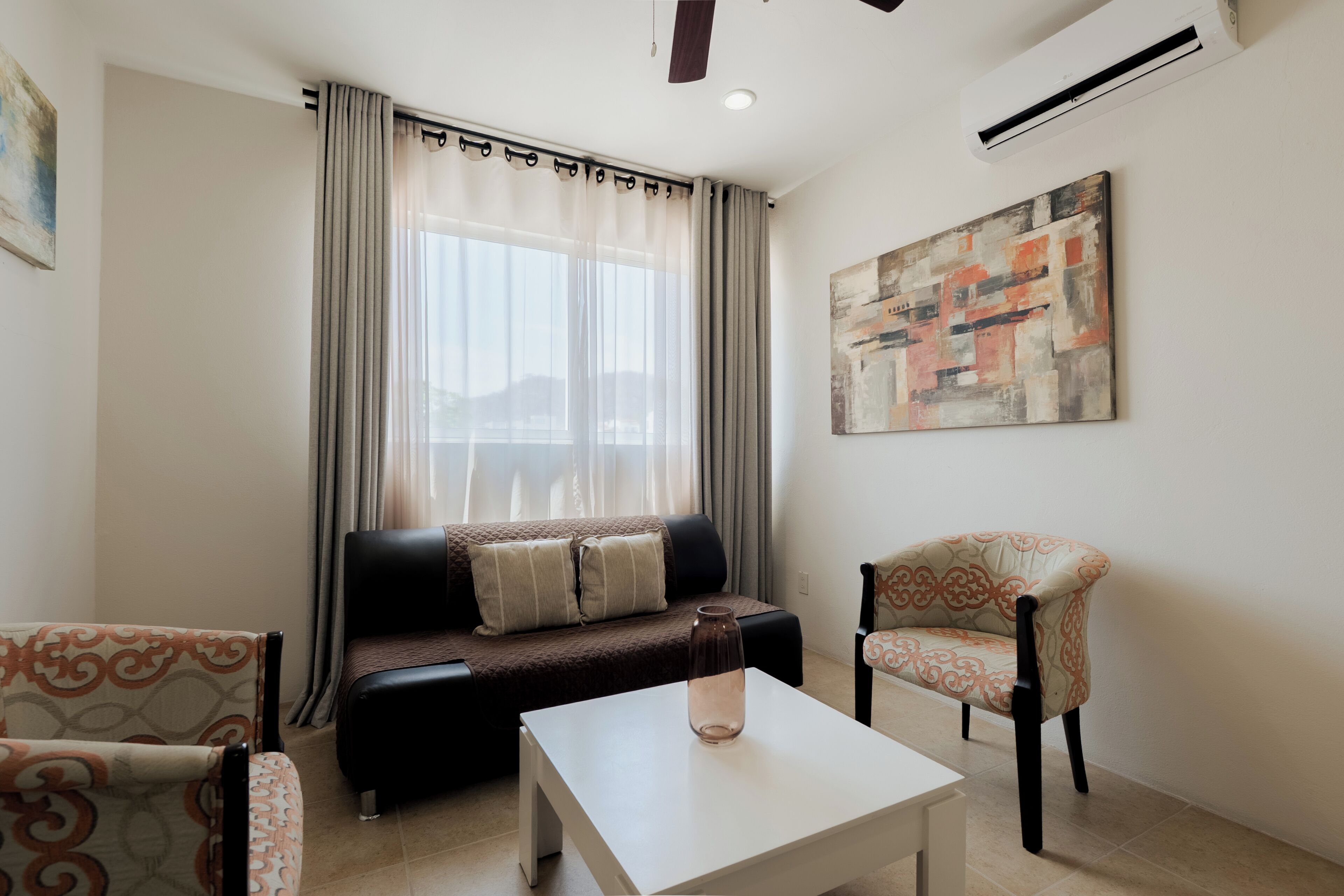 A living room with a sofa, a chair, a coffee table, and a painting on the wall.