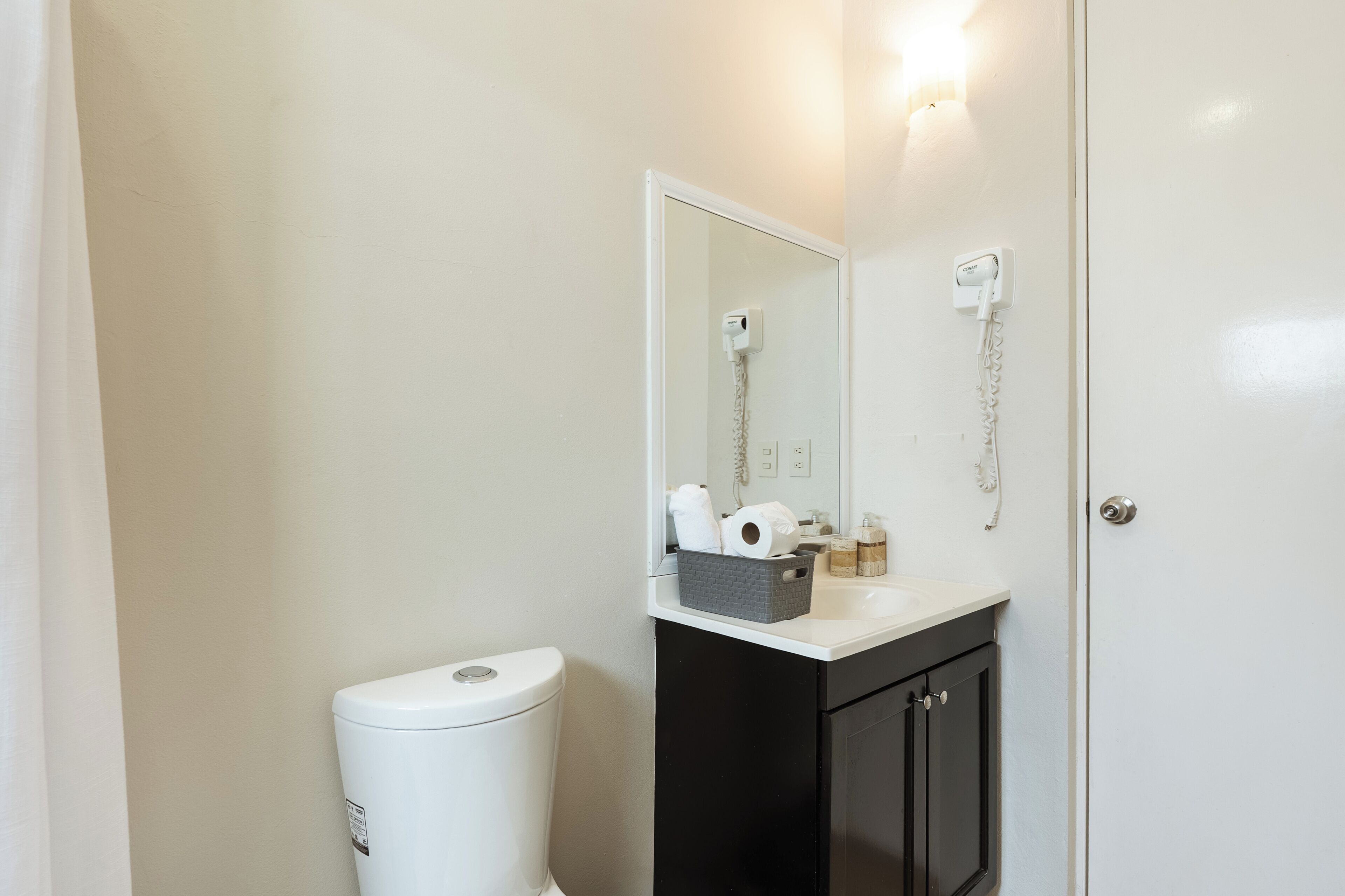 Un baño con inodoro, lavamanos con espejo y ducha.