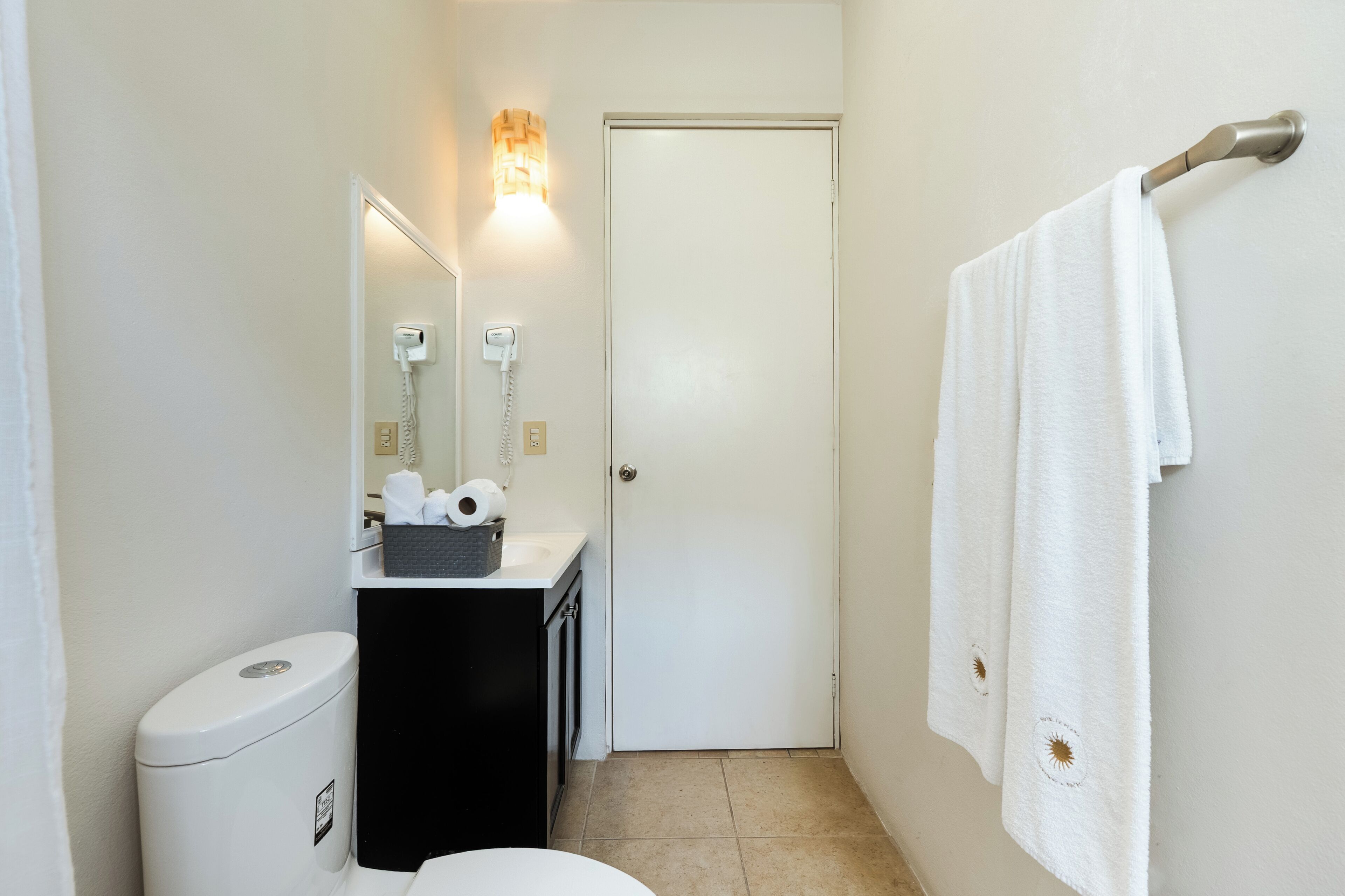 Un baño pequeño con inodoro, lavamanos y barra para toallas.