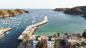 A coastal area with a pier extending into the water, surrounded by boats and buildings. - Suites La Playa (Santa Maria Huatulco)