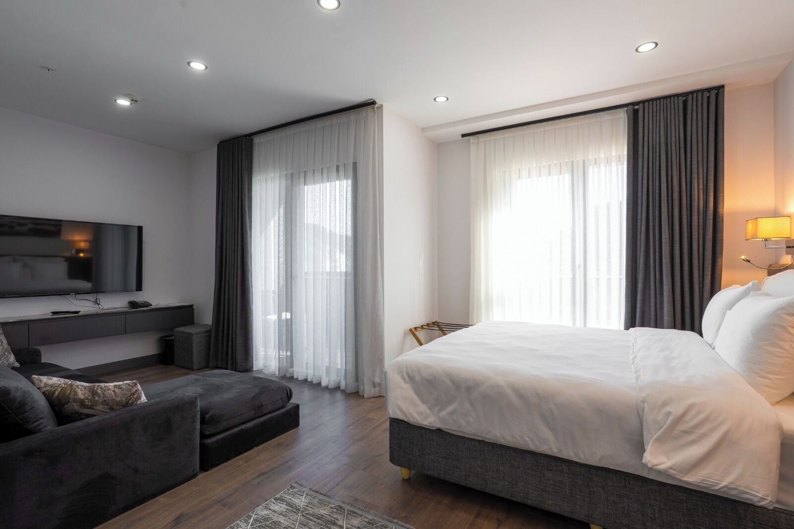 Una habitación de hotel moderna con una cama grande, un sofá, un televisor y un escritorio.