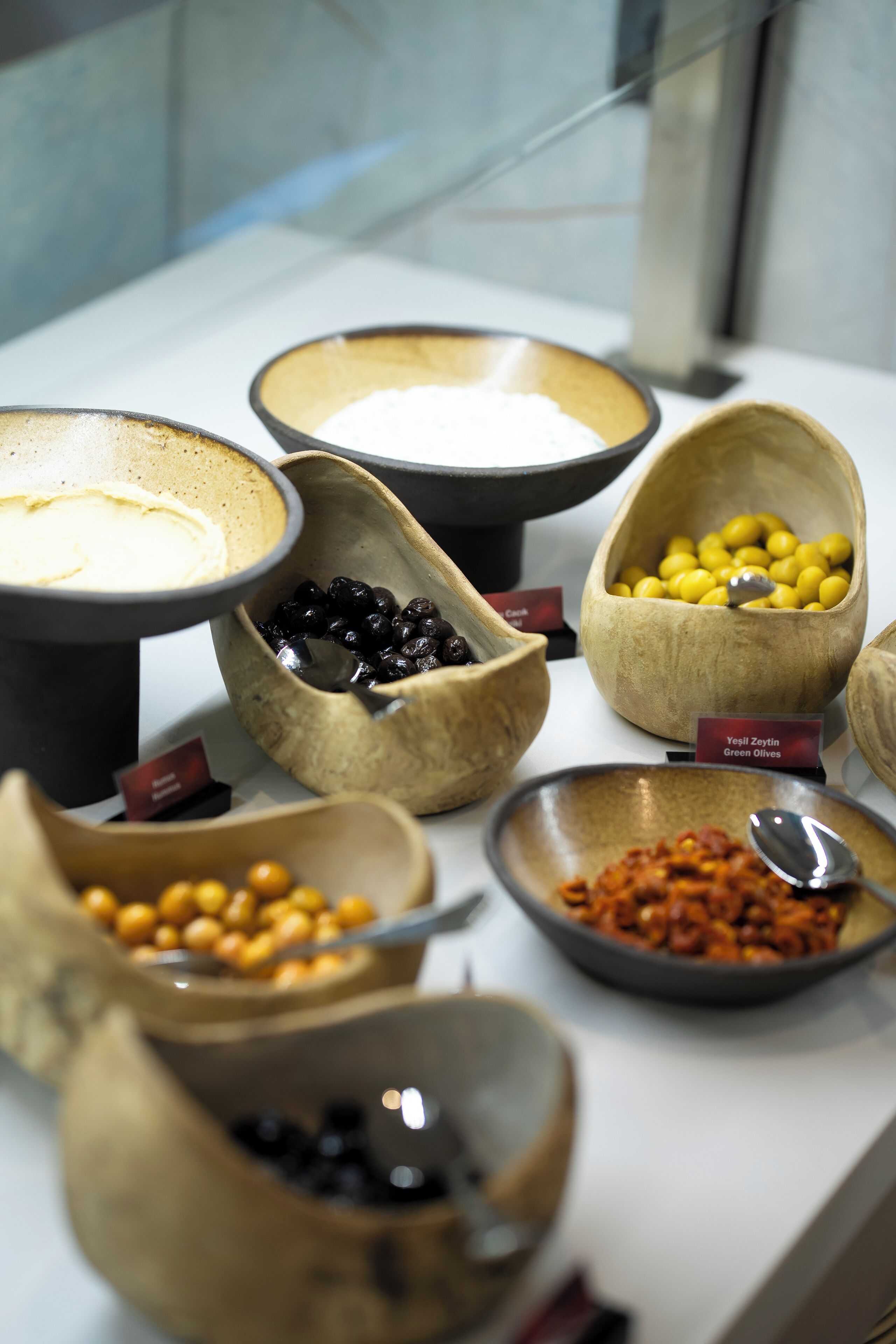 A display of various food items in bowls, including green olives, black olives, and other snacks.