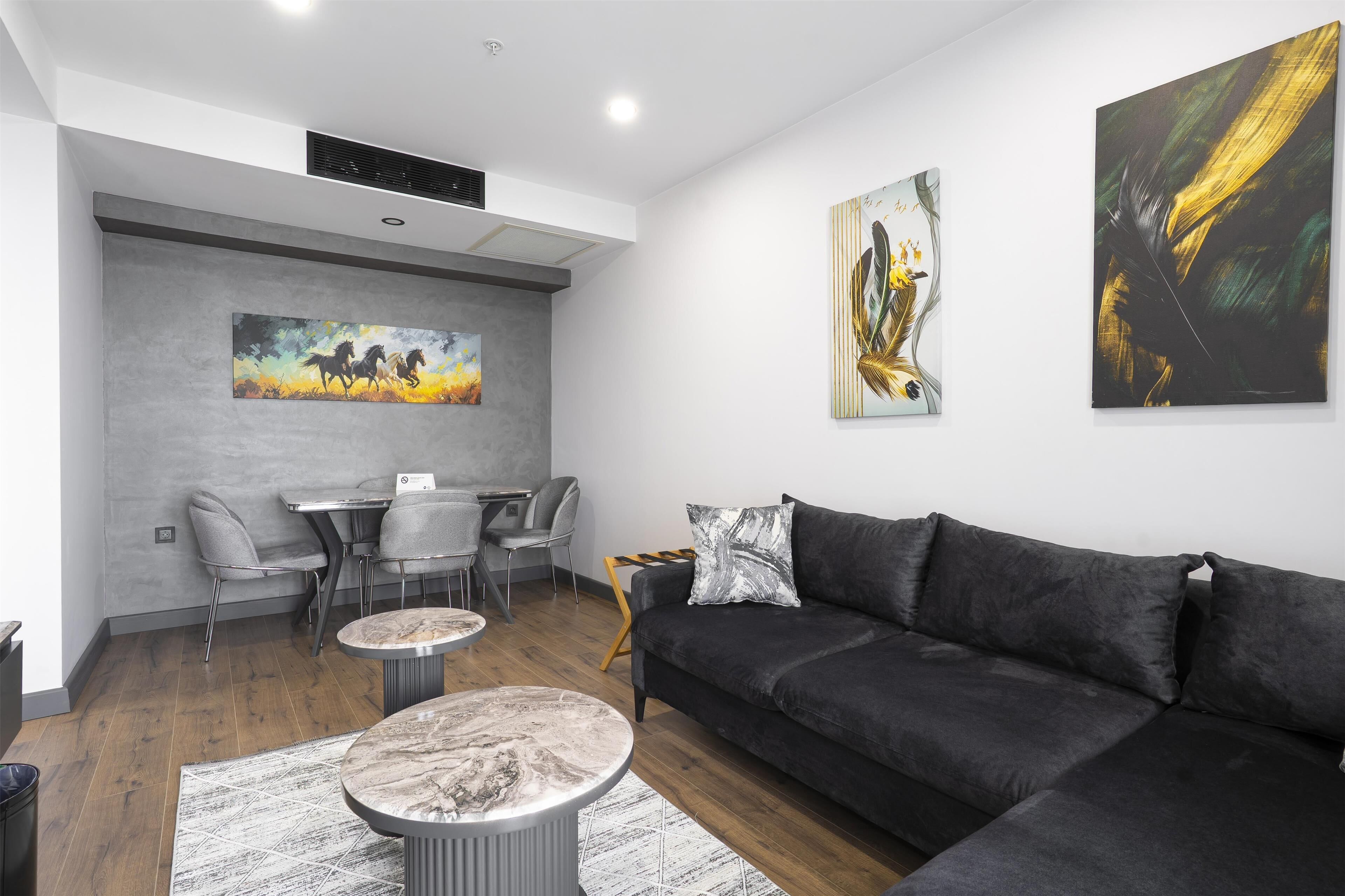 A modern living room with a sectional sofa, a dining area with a table and chairs, and artwork on the walls.