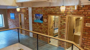 A multi-level interior with a wooden railing, brick walls, and numbered doors. - Pristine Hotel (Bishkek)