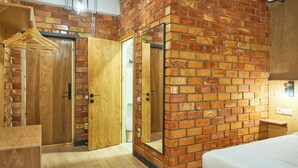 A room with a brick wall, wooden wardrobe, and a bed. - Pristine Hotel (Bishkek)