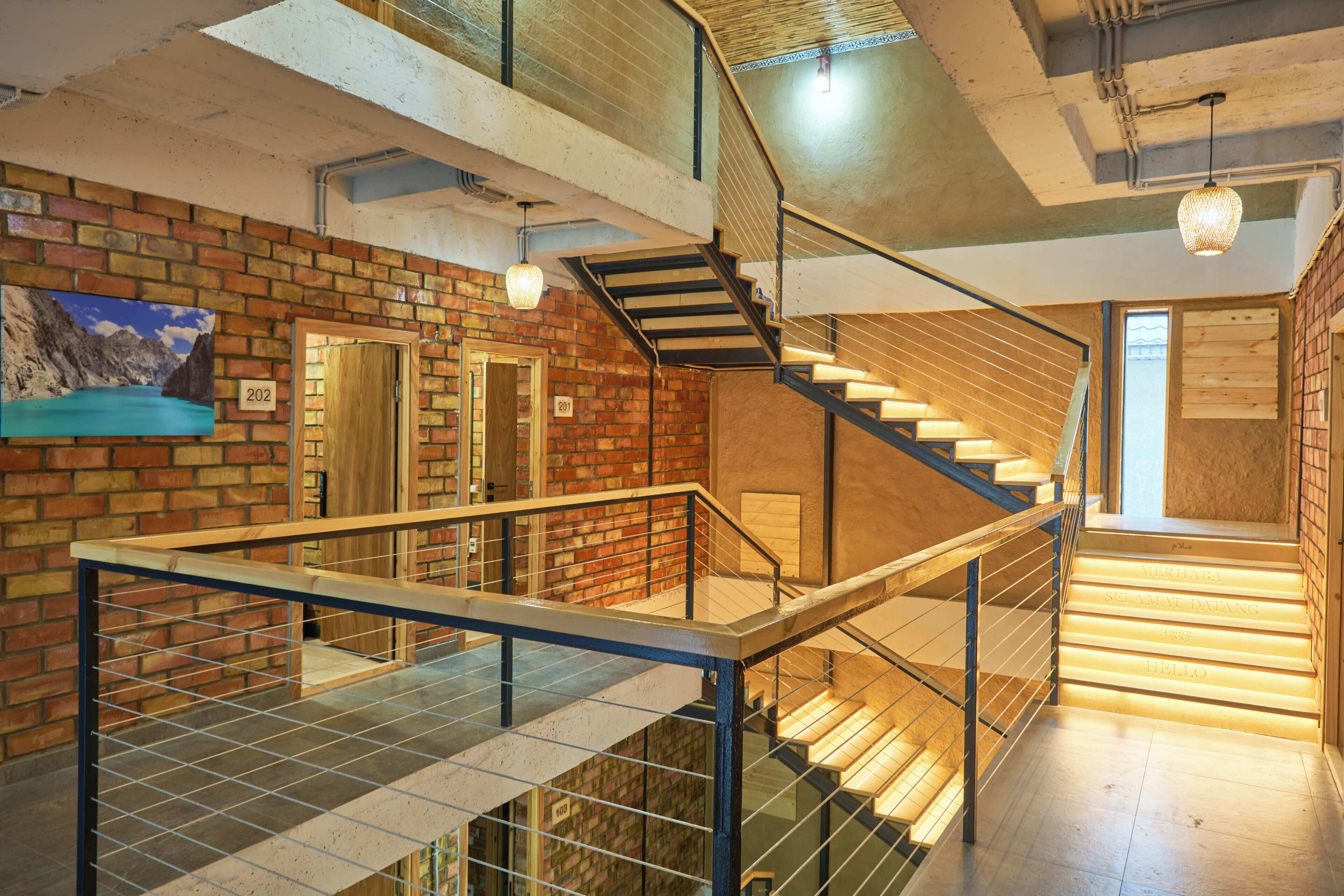 A multi-level interior with a staircase, a glass railing, and a brick wall.