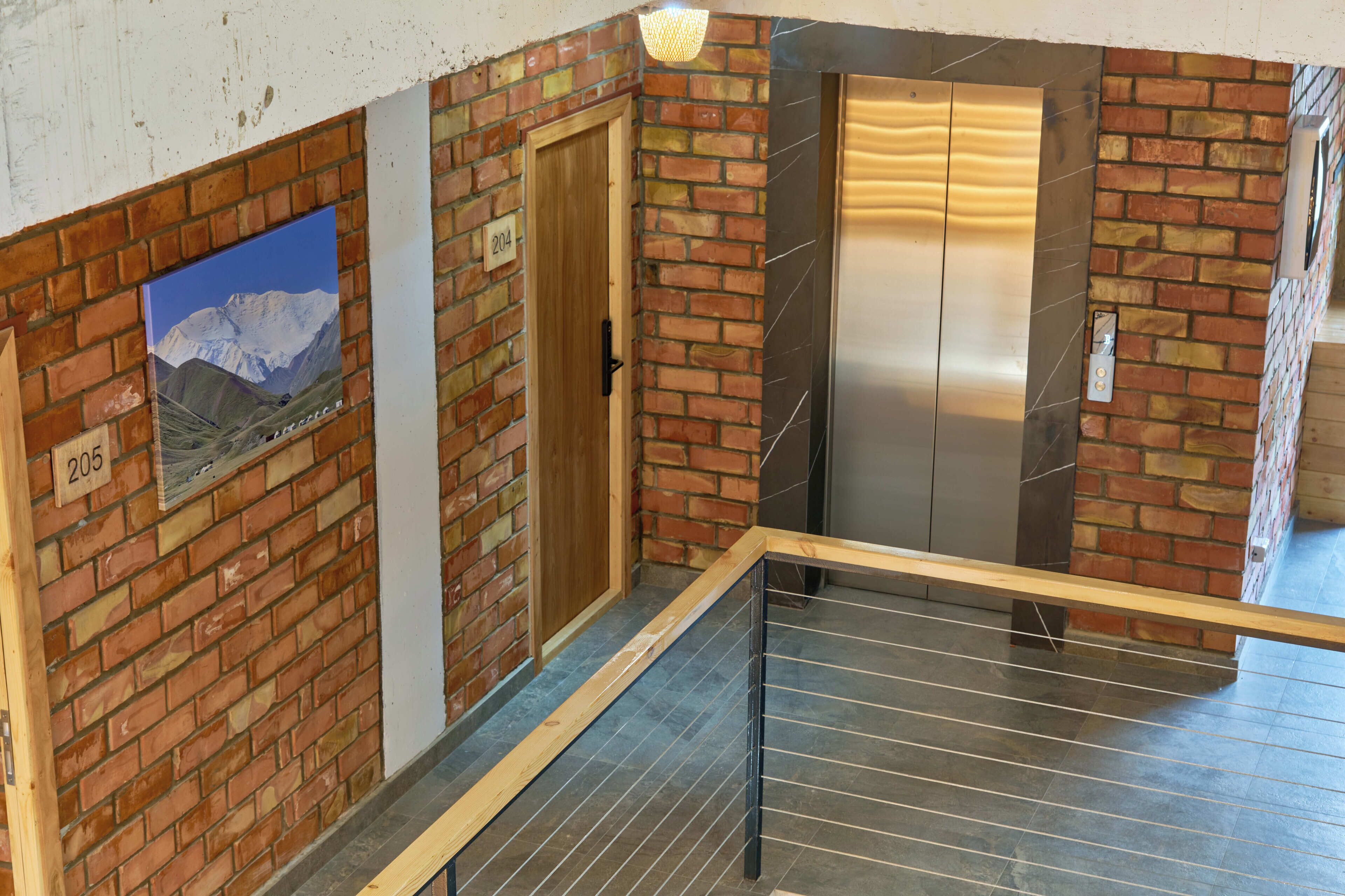 A staircase with a metal railing, a wooden door, and a brick wall with a poster.