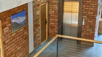 A staircase with a metal railing, a wooden door, and a brick wall with a poster.