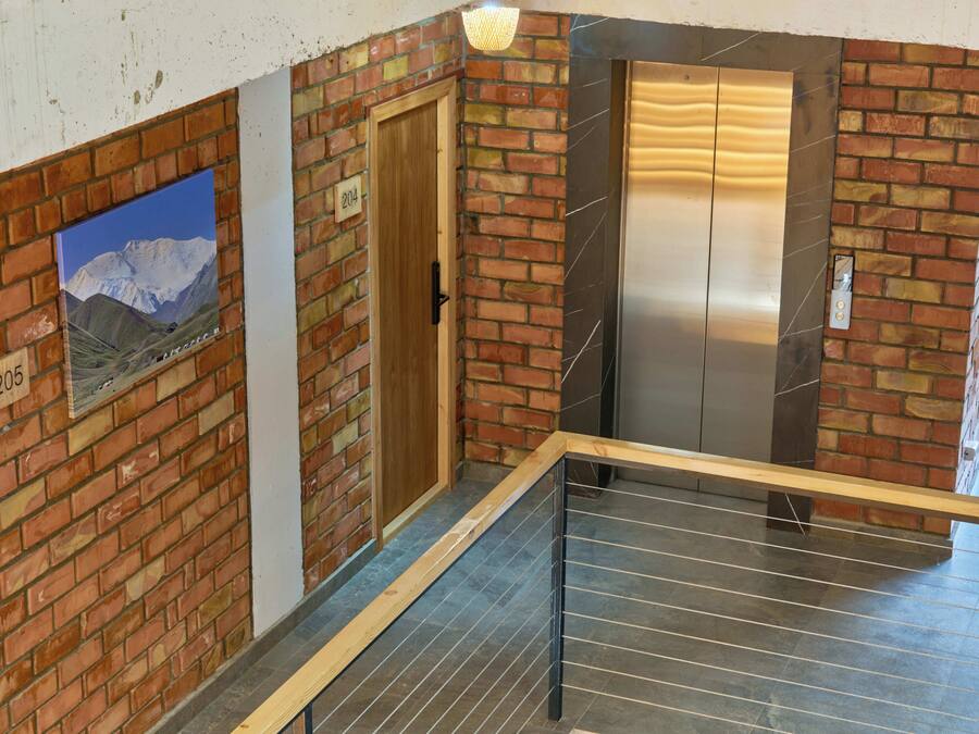 A staircase with a metal railing, a wooden door, and a brick wall with a poster.