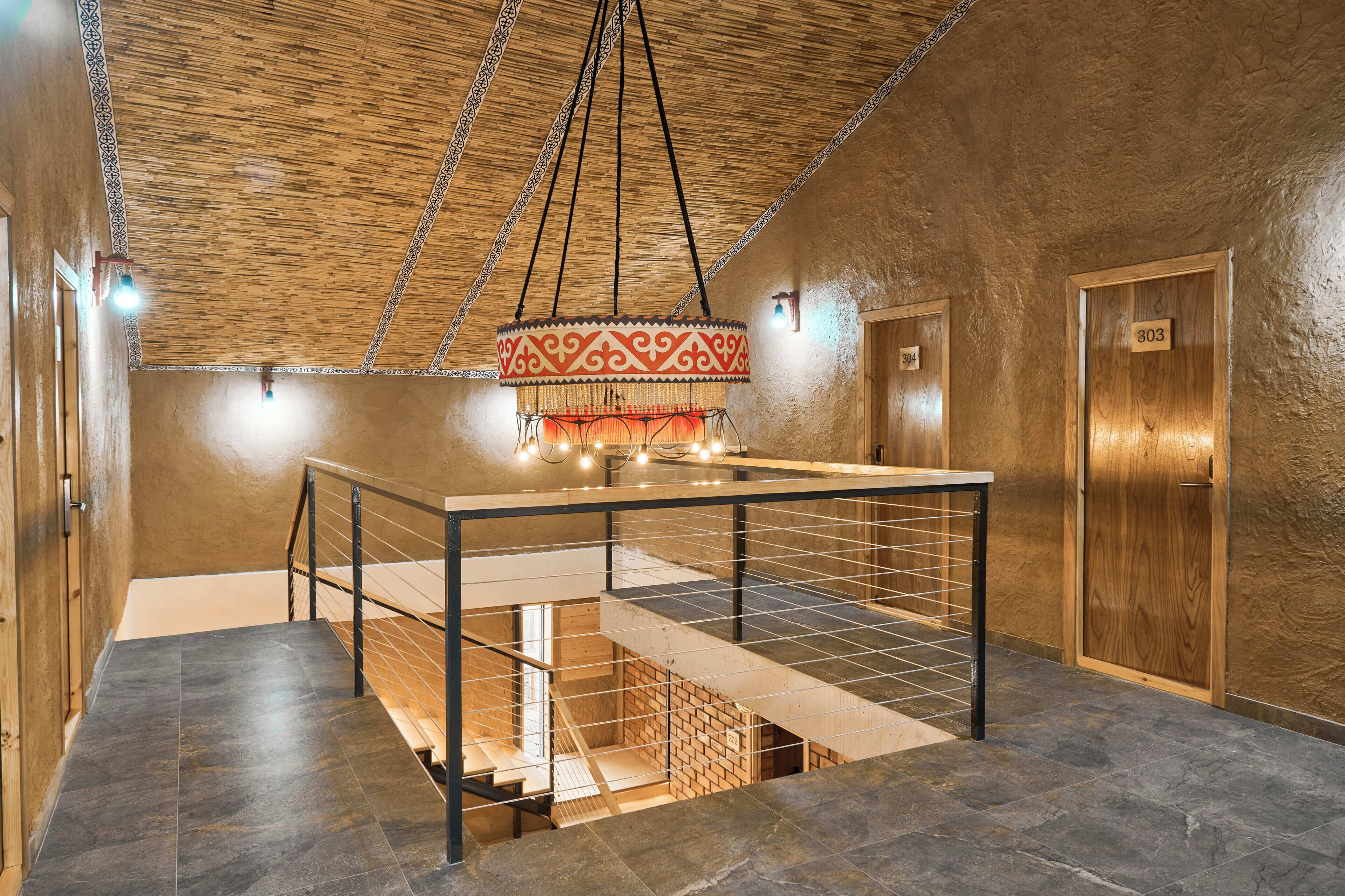 A hotel room with a wooden ceiling, a hanging light fixture, a wooden door with the number 303, and a tiled floor.