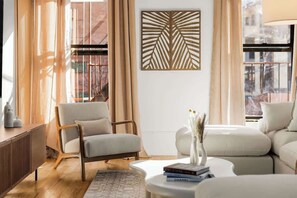 A modern living room with a sofa, armchair, and a decorative wall piece. - Spacious 3 Bedroom Gem in Trendy Dumbo! (Brooklyn)