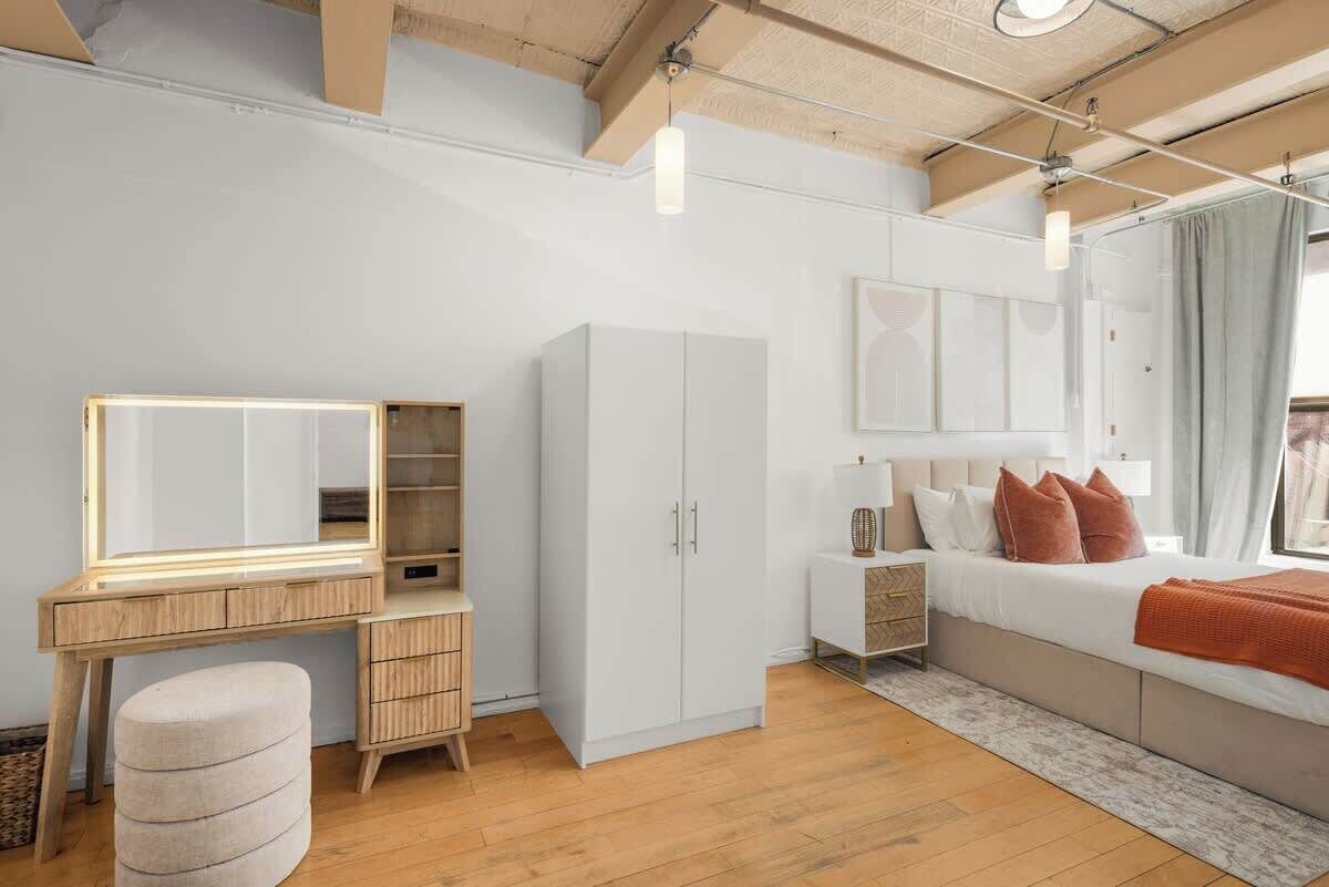 Une chambre à coucher comprenant un lit, une table de chevet, une armoire et une coiffeuse avec un miroir.