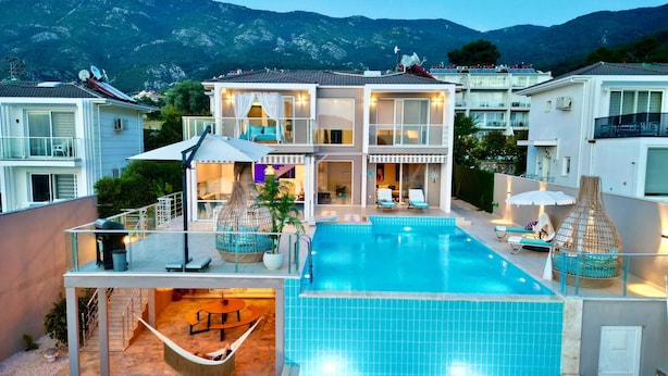 Un complexe hôtelier moderne doté d’une grande piscine, d’un espace extérieur aménagé et offrant une vue sur les montagnes.