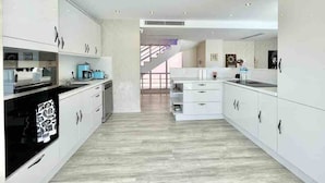 Une cuisine moderne avec des meubles blancs, un plan de travail noir et un plancher en bois.