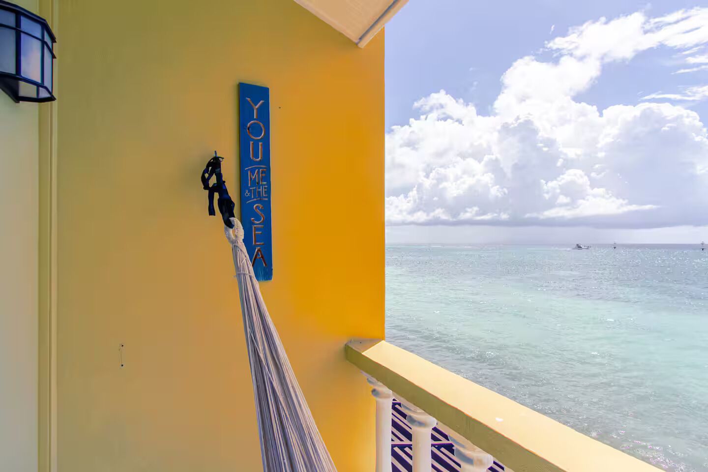 A room with a view of the sea, a hammock, and a sign that reads "YOU ME & THE SEA".