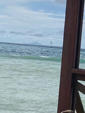 Een houten constructie met uitzicht op de oceaan en een eiland in de verte.