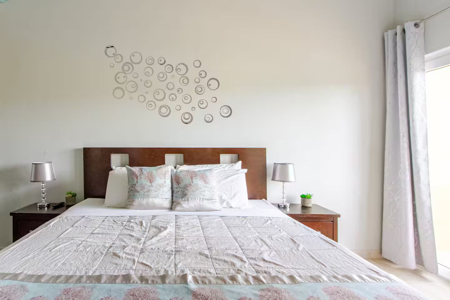 Een slaapkamer met een groot bed, twee nachtkastjes en een decoratie aan de muur.