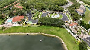 An aerial view of a residential area with a swimming pool, landscaped gardens, and a roundabout. - Magnificent Lake View - Spacious 5-bdrm Pool Home - Close to Disney (Kissimmee)