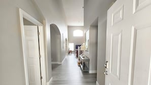 A hallway with white doors, a wooden floor, and a view of a bedroom with a bed and dresser. - Magnificent Lake View - Spacious 5-bdrm Pool Home - Close to Disney (Kissimmee)