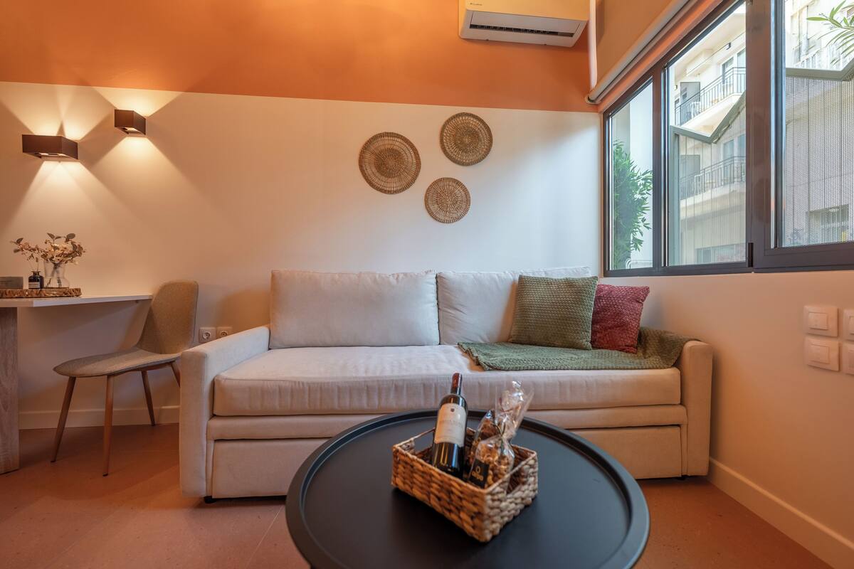 Un salon moderne avec un canapé, une table basse sur laquelle se trouvent une bouteille et un verre, et des éléments de décoration fixés au mur.