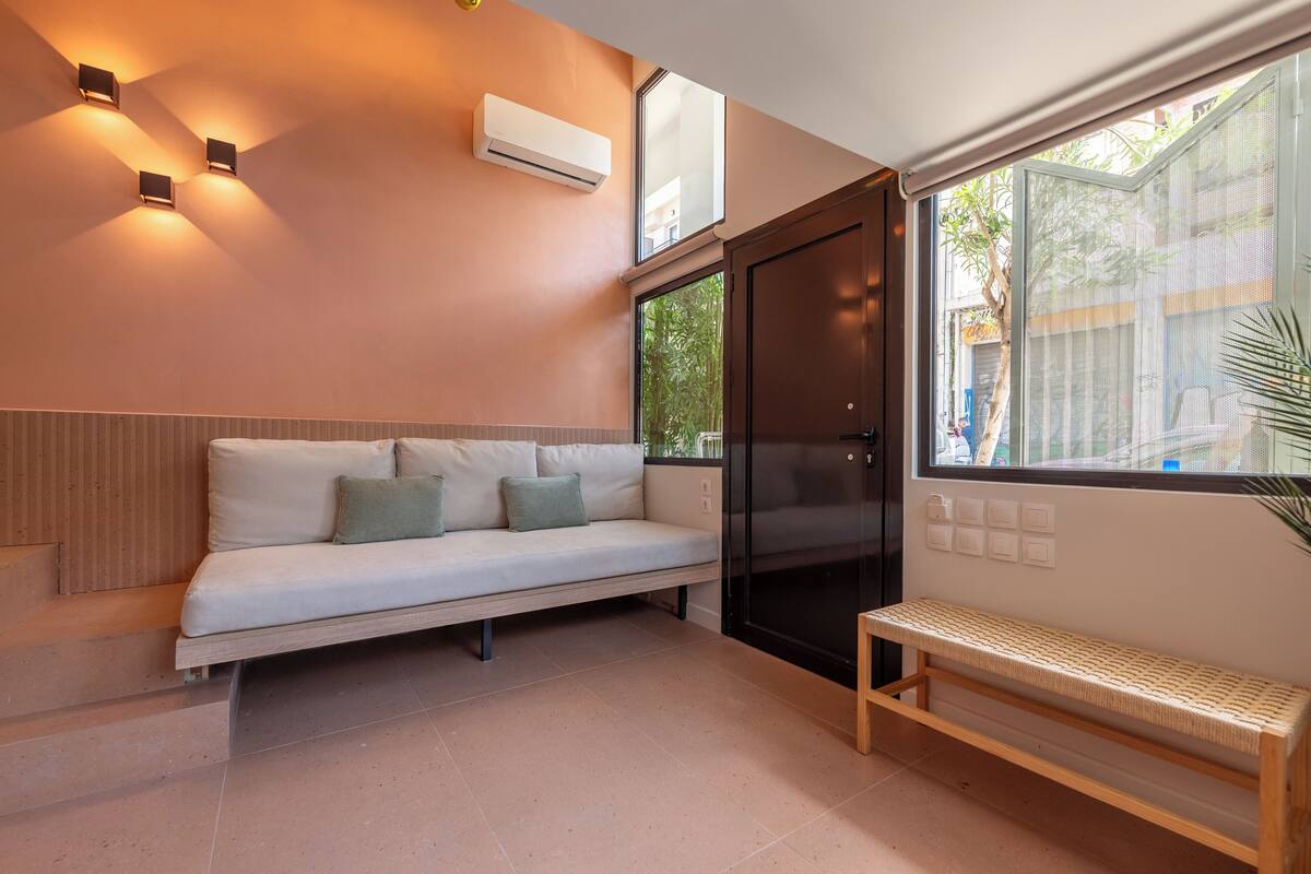 Une pièce moderne comprenant un canapé, un banc et une porte coulissante donnant sur un balcon.